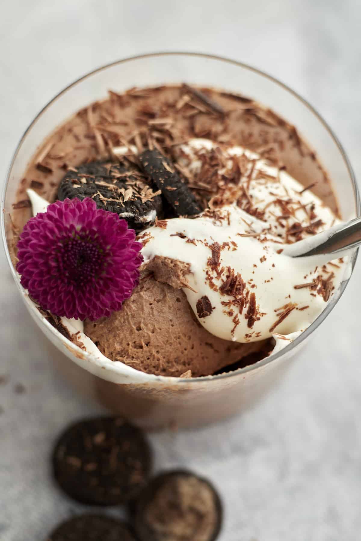 oreo chocolate mousse in one ramekin with spoon, garnished with whipped cream, chocolate, and oreo cookies.