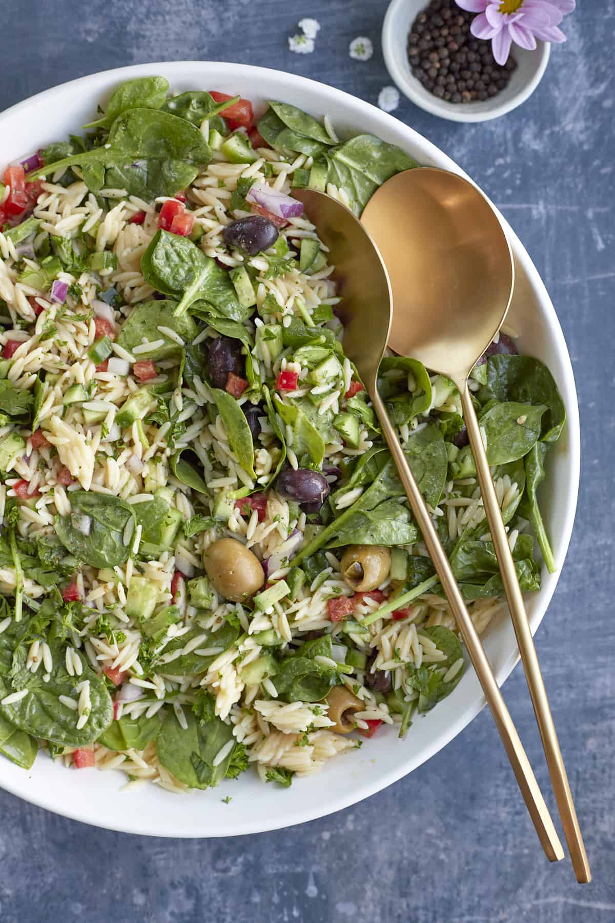 overhead of greek orzo pasta salad with serving spoons