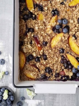close up overhead image of peach blueberry baked oats in a baking dish
