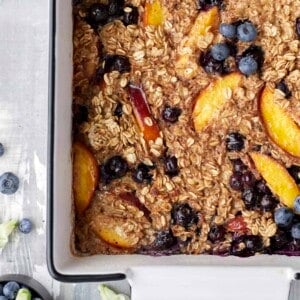 close up overhead image of peach blueberry baked oats in a baking dish