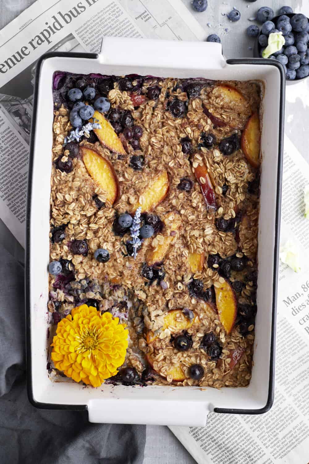 overhead of blueberry baked oats in a baking dish over newspaper