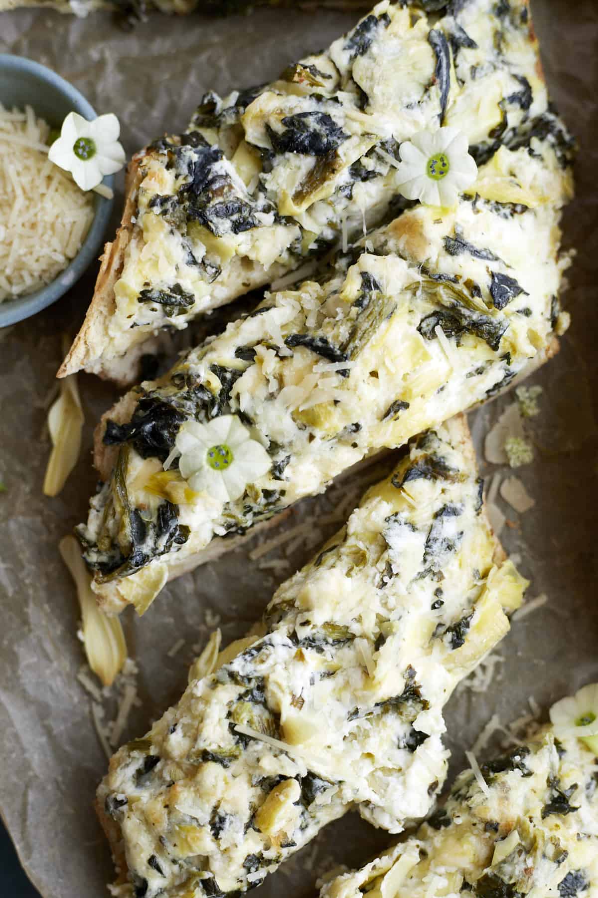 sliced pieces of homemade garlic bread with spinach and artichokes