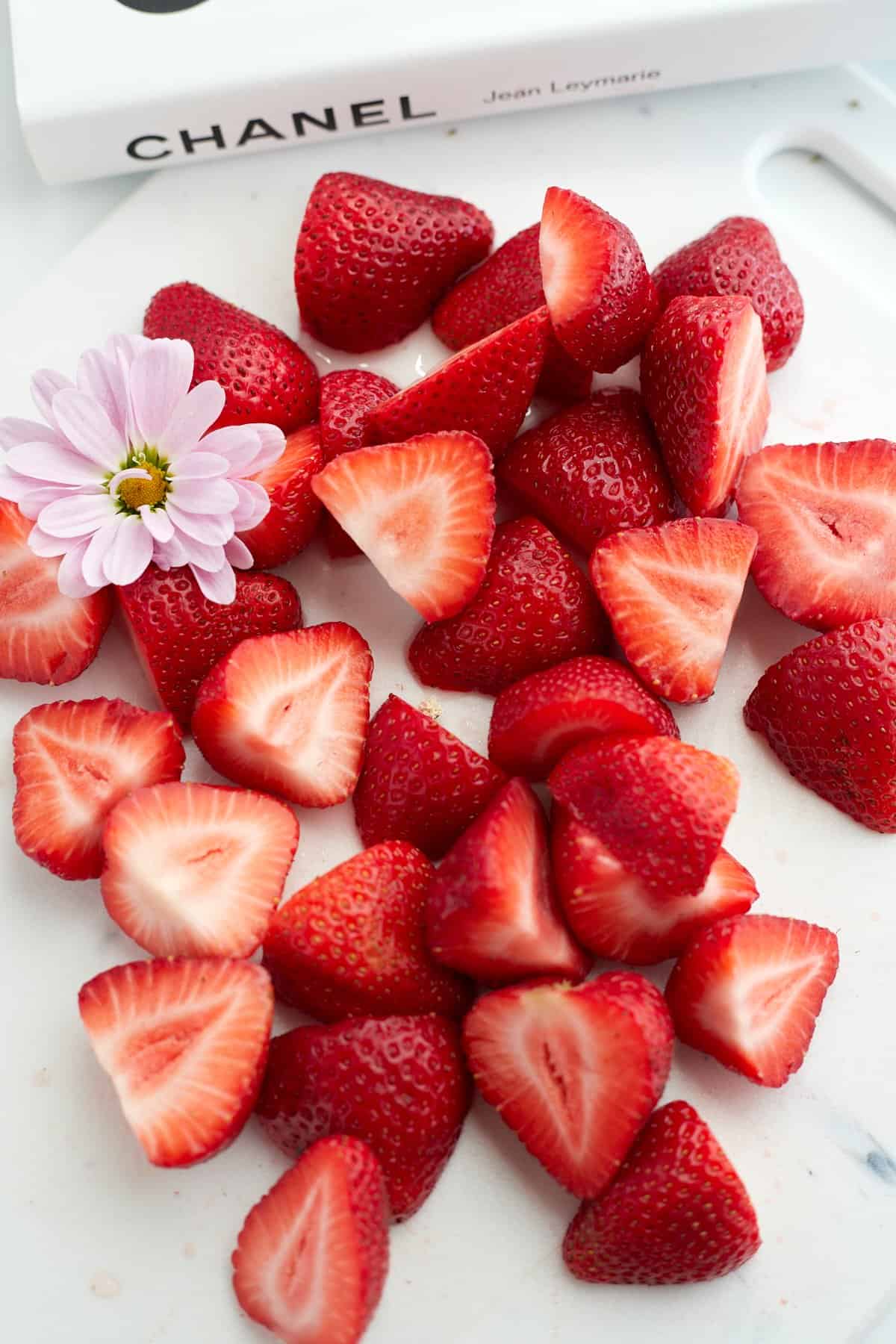 Chopped strawberries with a small flower on a cutting board