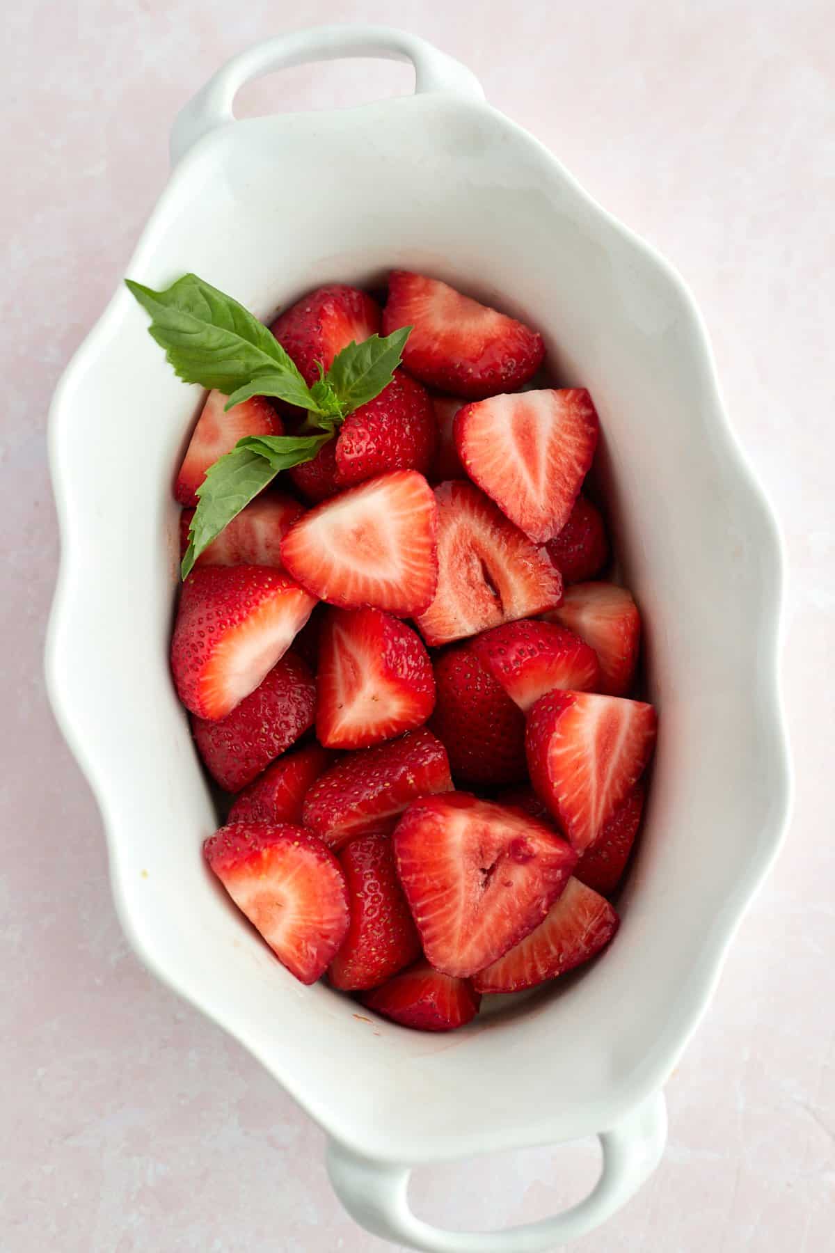 Strawberries in a baking dish with fresh basil