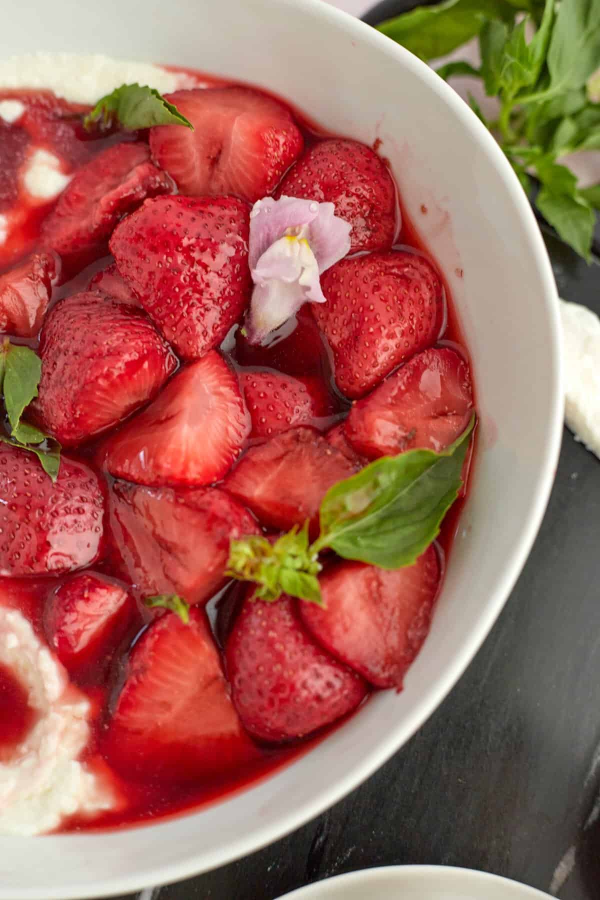 Whipped goat cheese and strawberries in a bowl with fresh basil