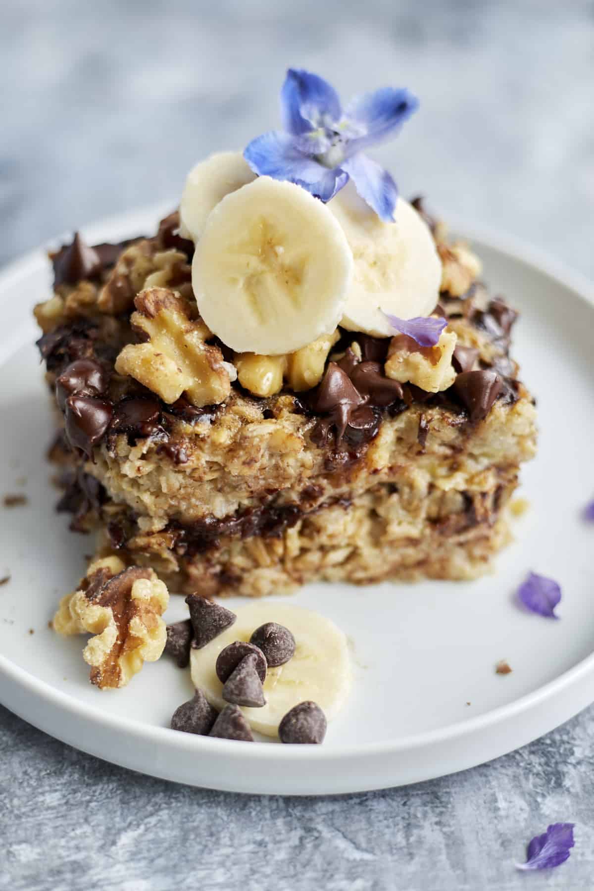 Banana Bread Oatmeal on a white plate topped with banana coins, walnuts, and chocolate chips