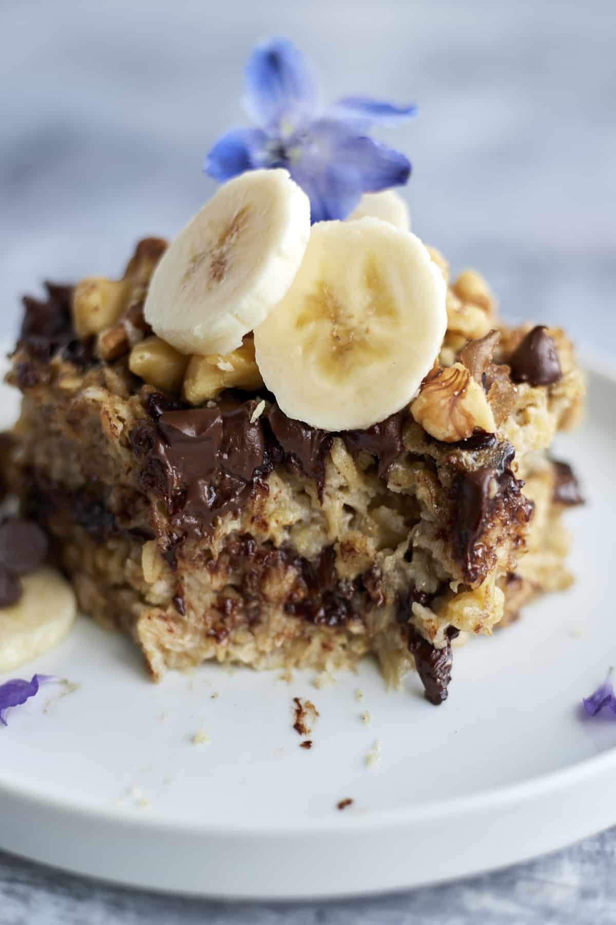Banana Bread Oatmeal on a white plate topped with walnuts and banana coins with a bite taken out