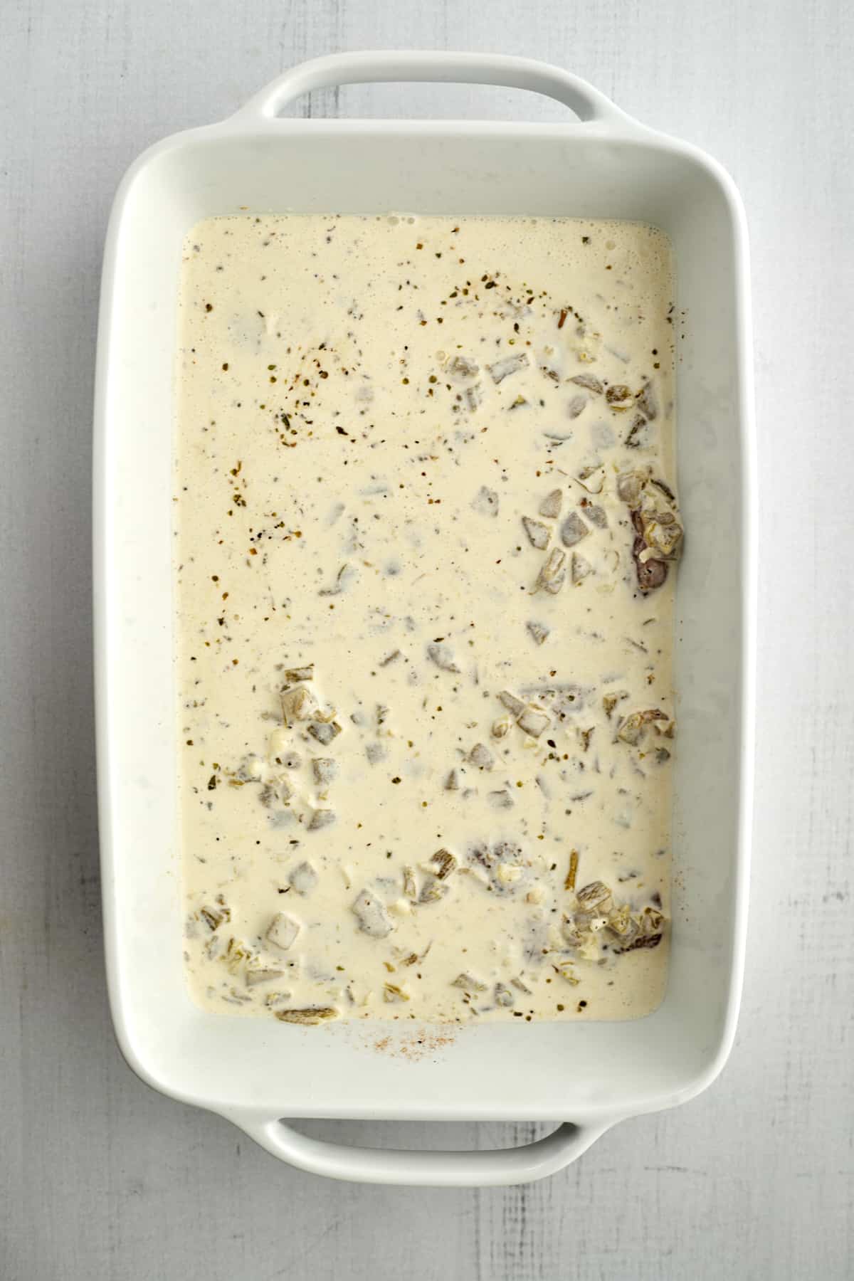 a creamy sauce with onions in the bottom of a baking dish