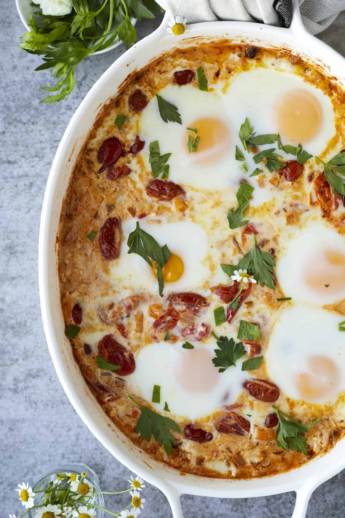 close up image of oven baked eggs with feta and veggies topped with fresh herbs.