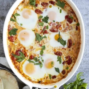 overhead image of 6 oven baked eggs in a baking dish with feta and veggies