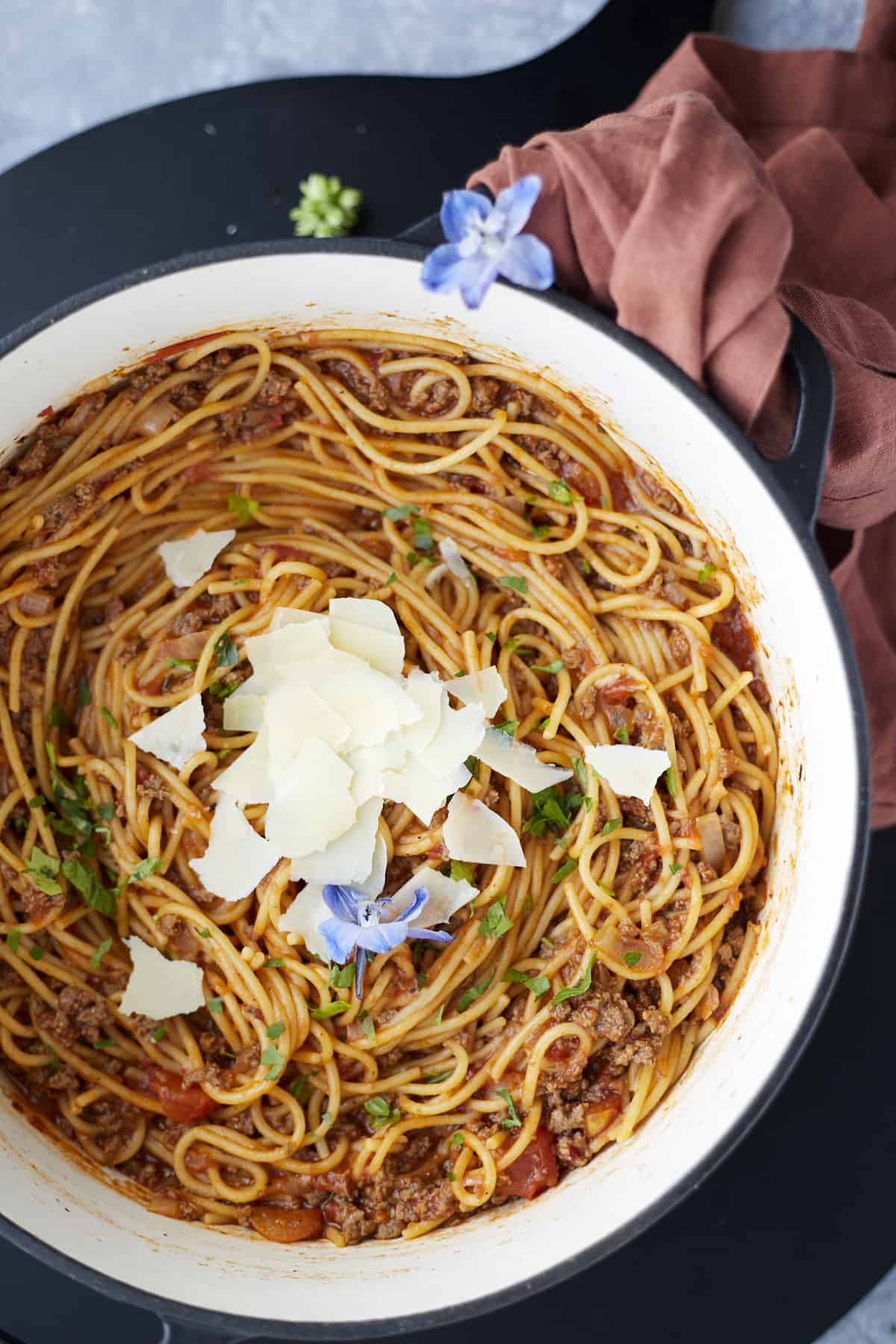 overhead image of one pot spaghetti recipe with ground beef in a large pot topped with shaved Parmesan.