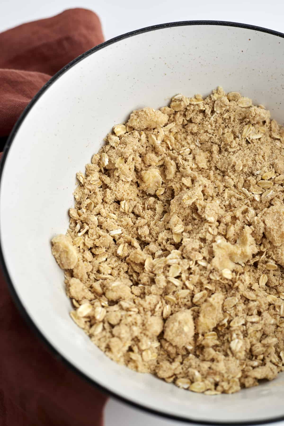 oat and flour topping in a white bowl for a peach crisp.