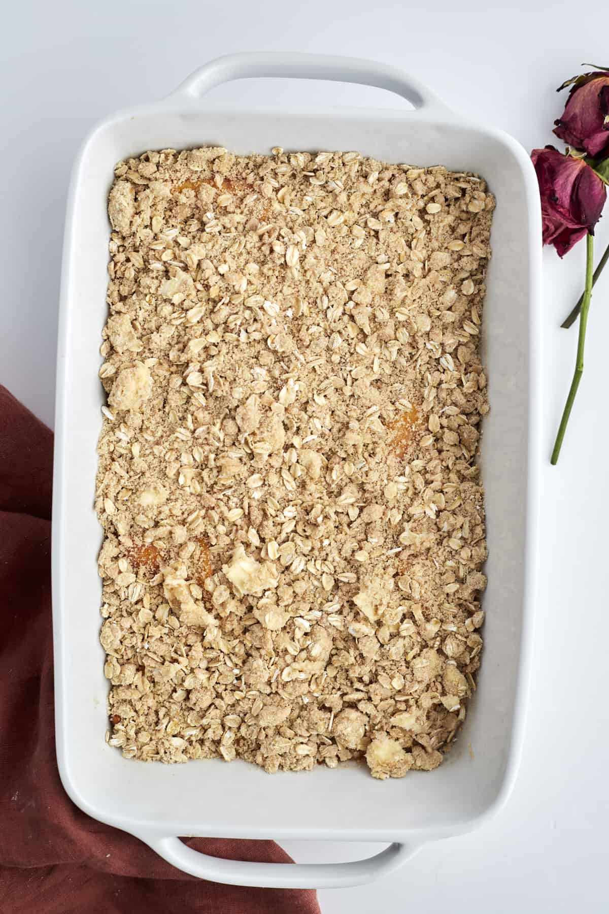 overhead image of an unbaked peach crisp in a white baking dish