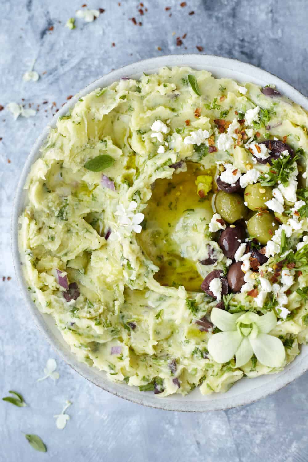 overhead image of Greek-Inspired Yukon Gold Mashed Potatoes topped with olives, feta cheese, olive oil, and red pepper flakes.