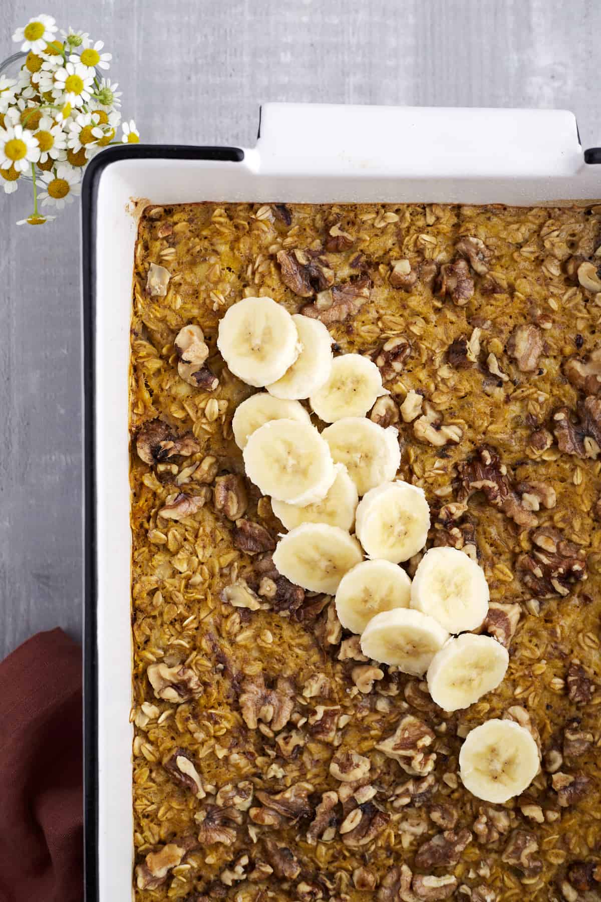 overhead image of baked pumpkin oatmeal topped with pecans and banana coins