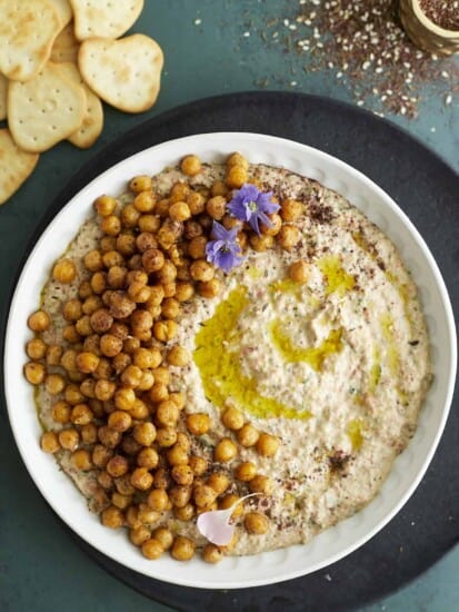 overhead image of the best baba ganoush recipe in a white bowl topped with crispy chickpeas and olive oil with crackers on the side