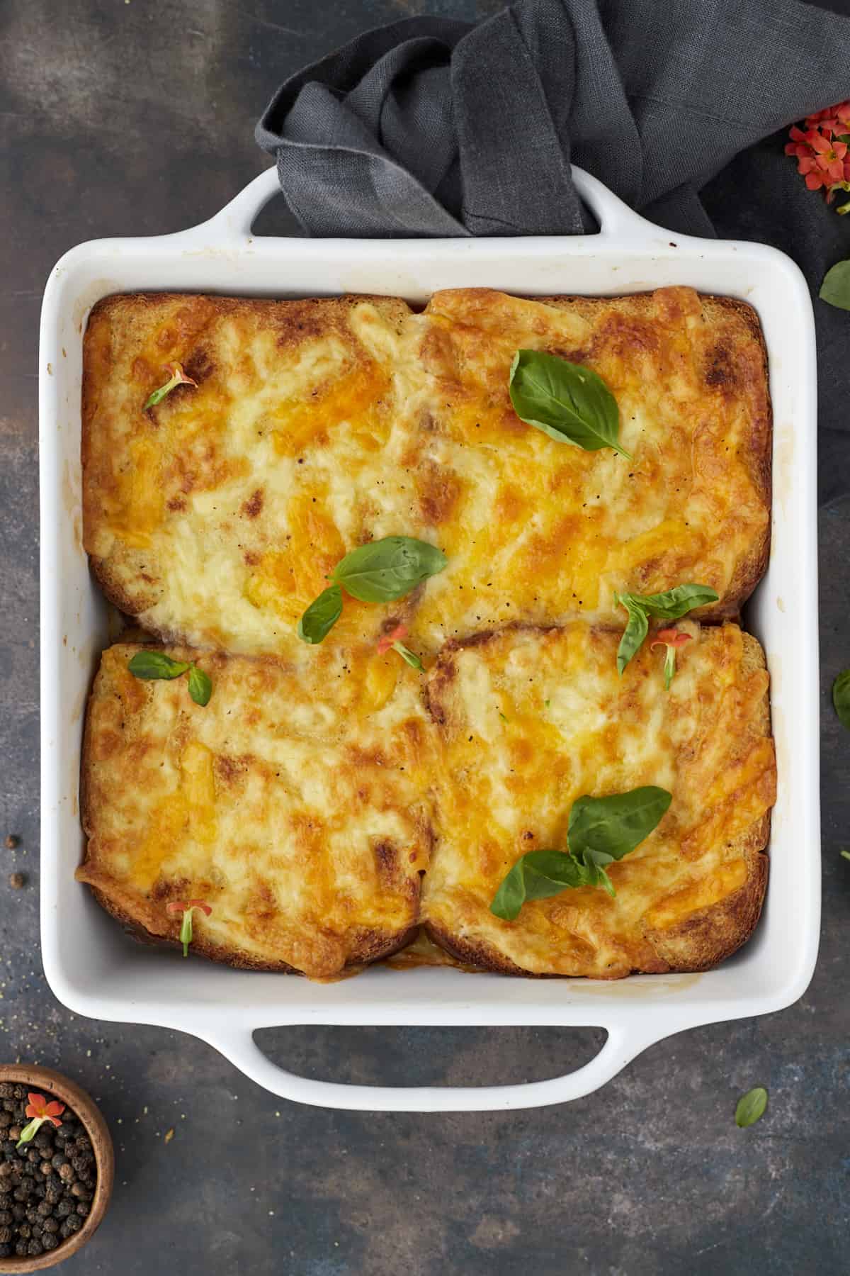 four baked chicken fajita sandwiches topped with golden cheese in a white square baking dish