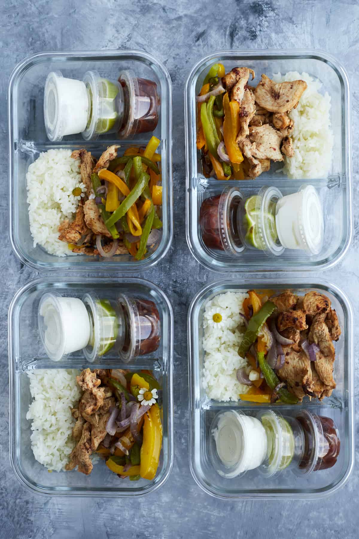 four meal prep boxes full of chipotle chicken with white rice, salsa, guacamole, and sour cream