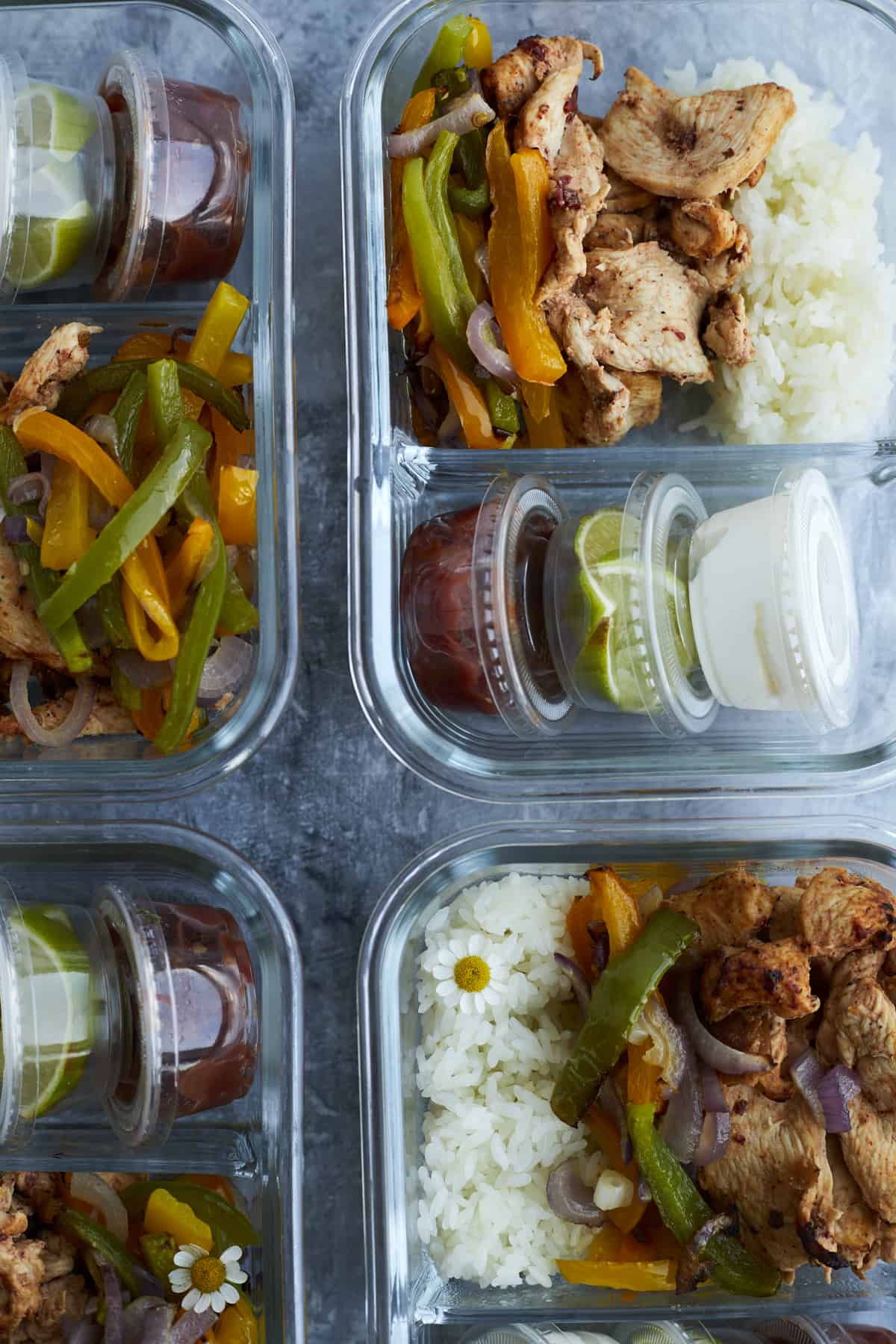 meal prep boxes of chipotle chicken with peppers, onions, white rice, salsa, guacamole, and sour cream