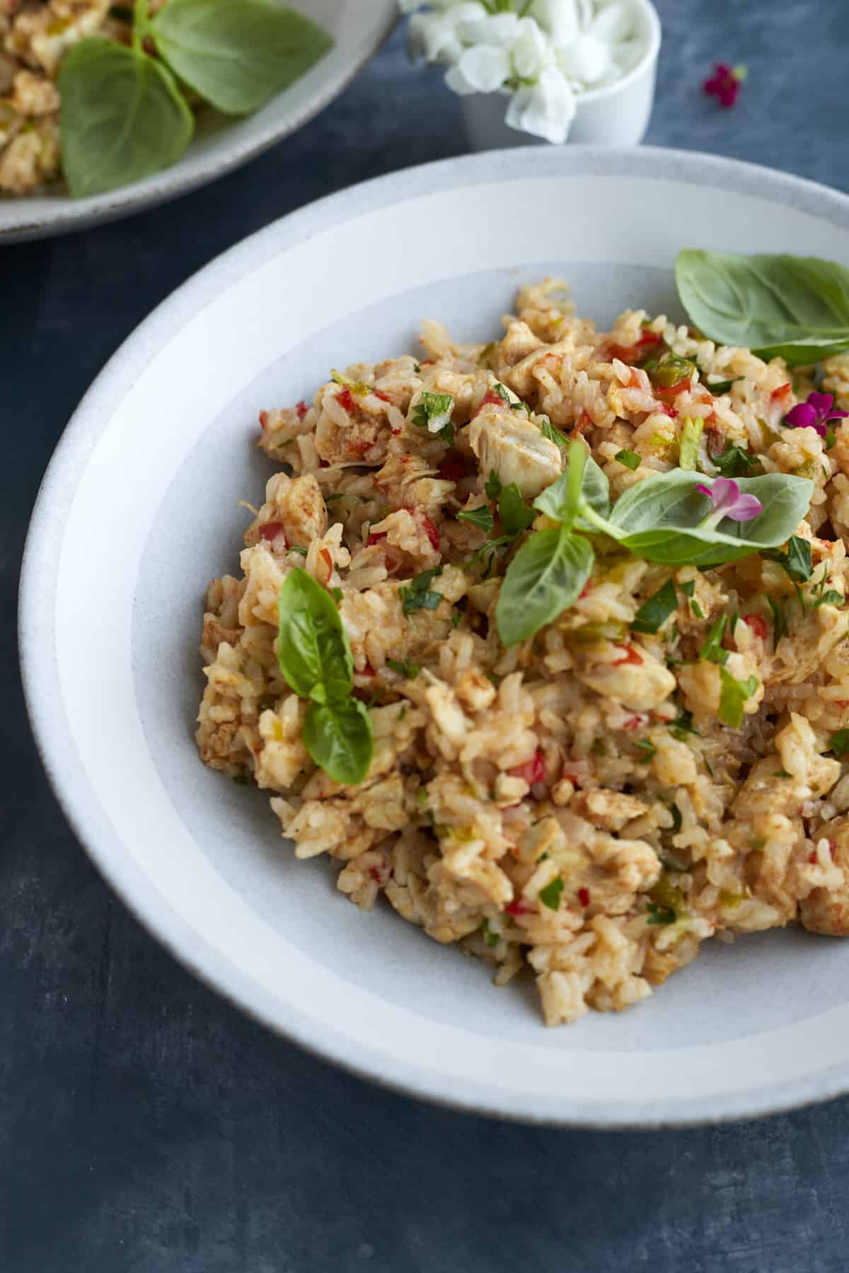 a close up image of a white bowl full of fajita seasoned rice topped with fresh herbs