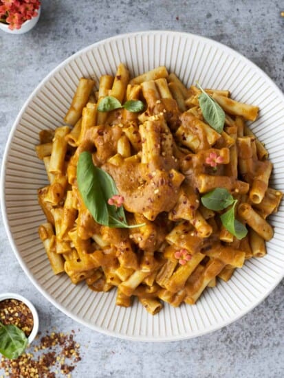 overhead image of veggie pasta topped with fresh herbs in a white bowl