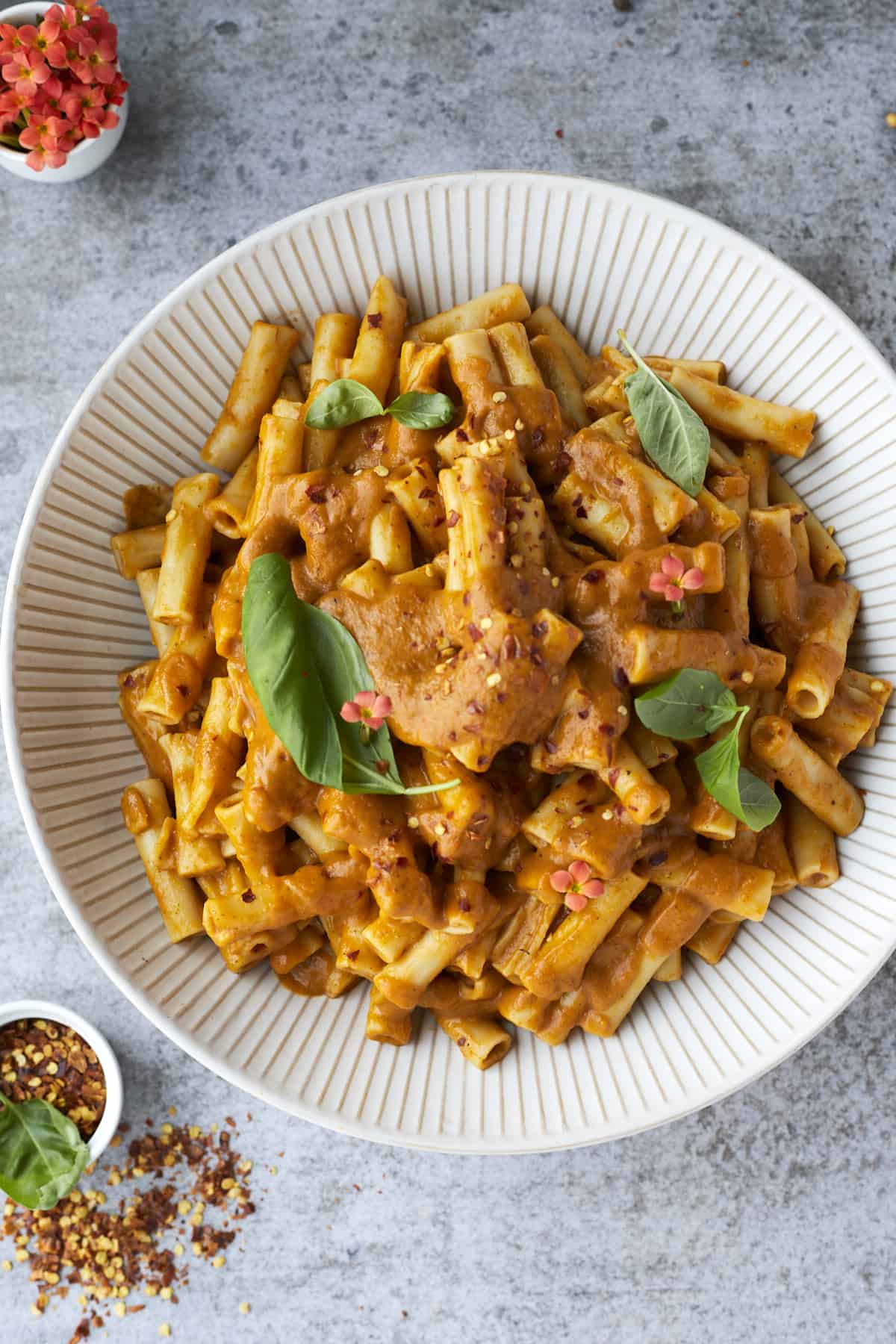 overhead image of a white bowl full of veggie pasta topped with fresh herbs