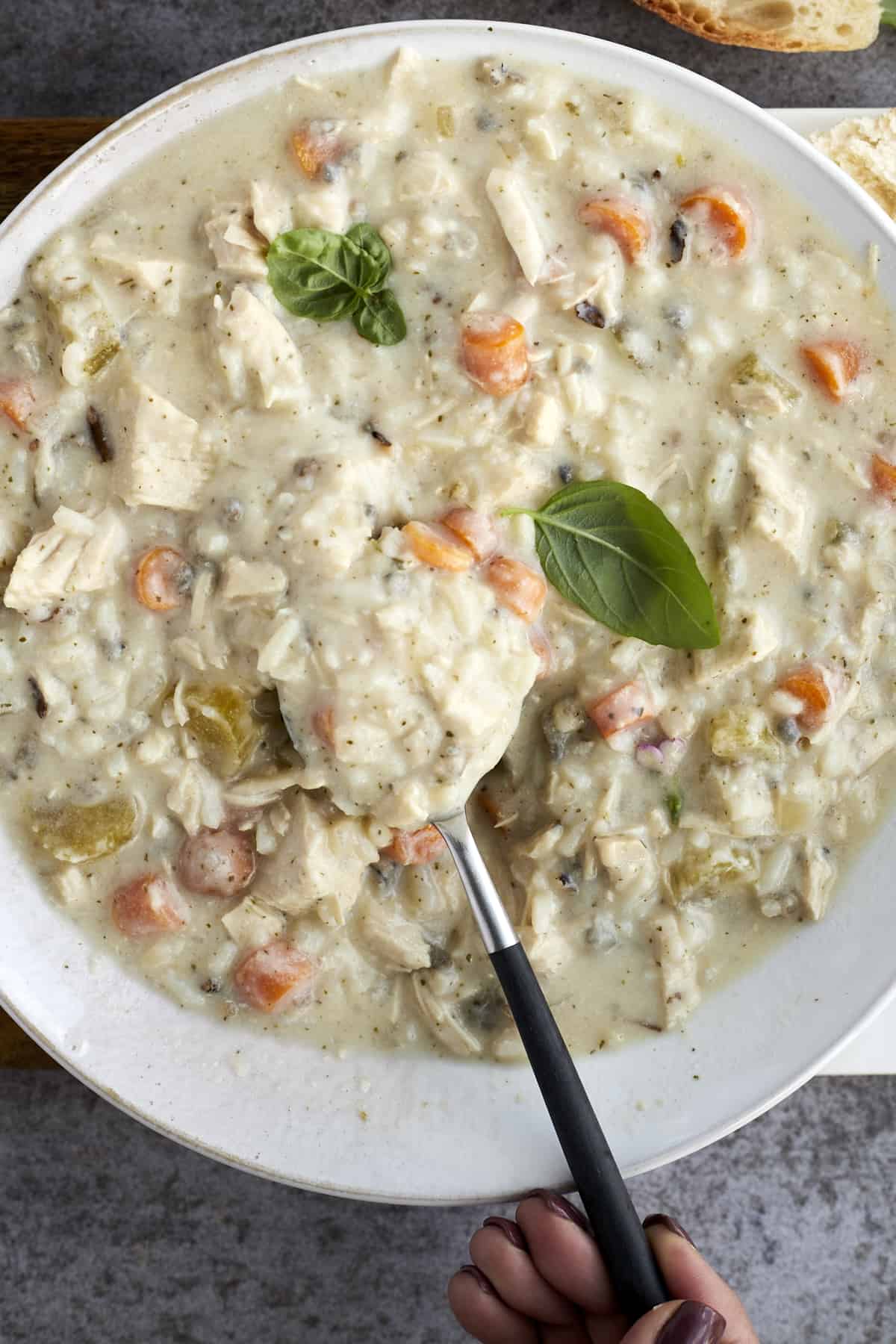 creamy chicken wild rice soup in a bowl with a spoon sticking out 
