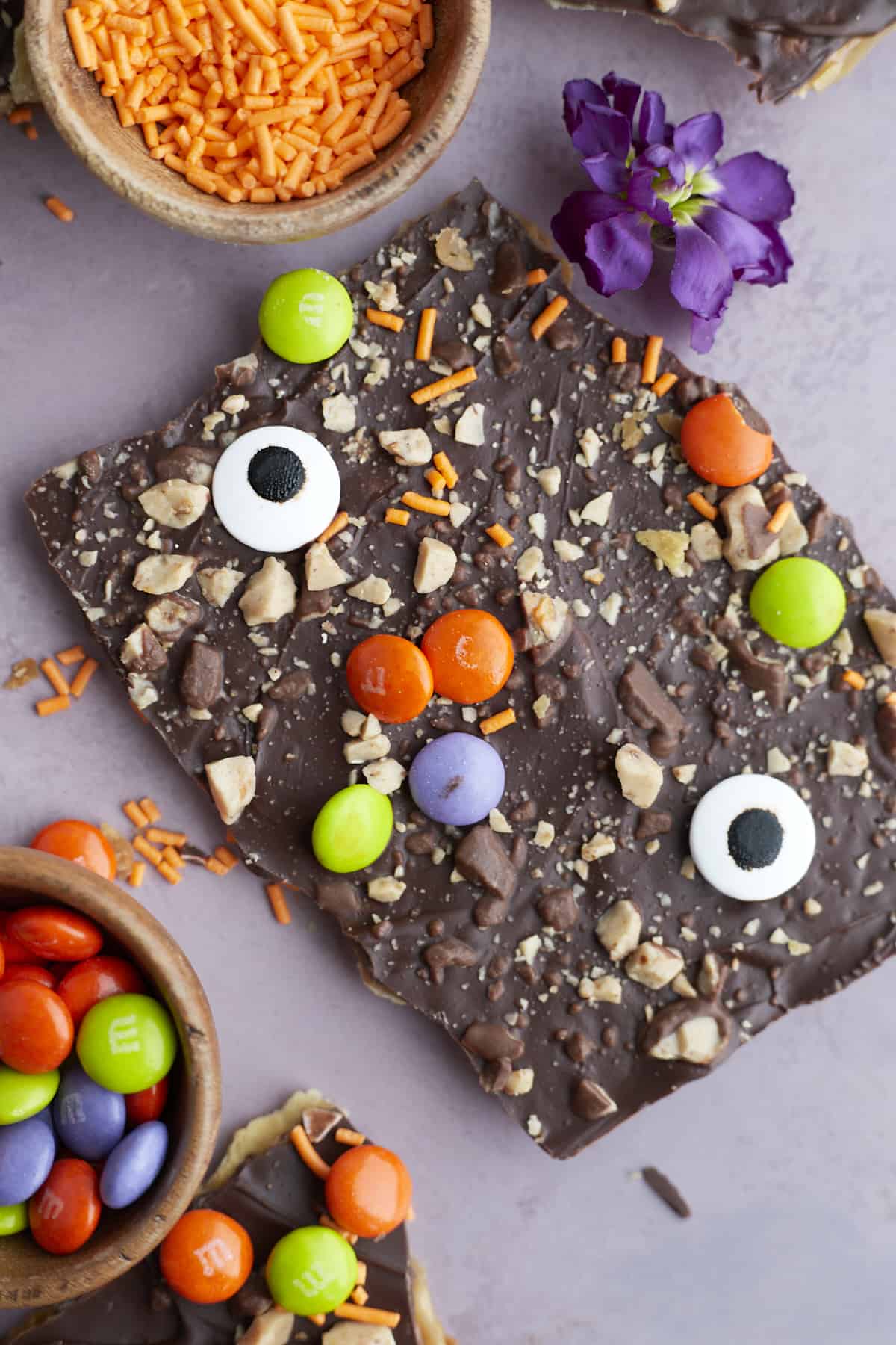 two pieces of Halloween saltine crack candy decorated with toffee, M&Ms, and candy eyeballs