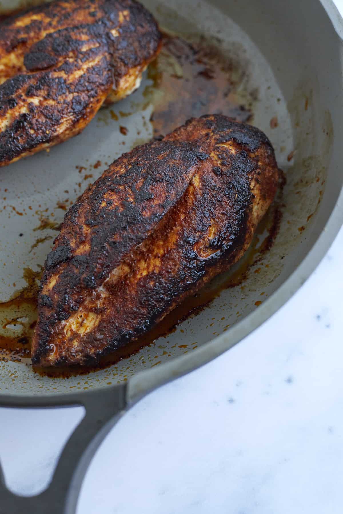 cooked seasoned chicken breasts in a skillet.