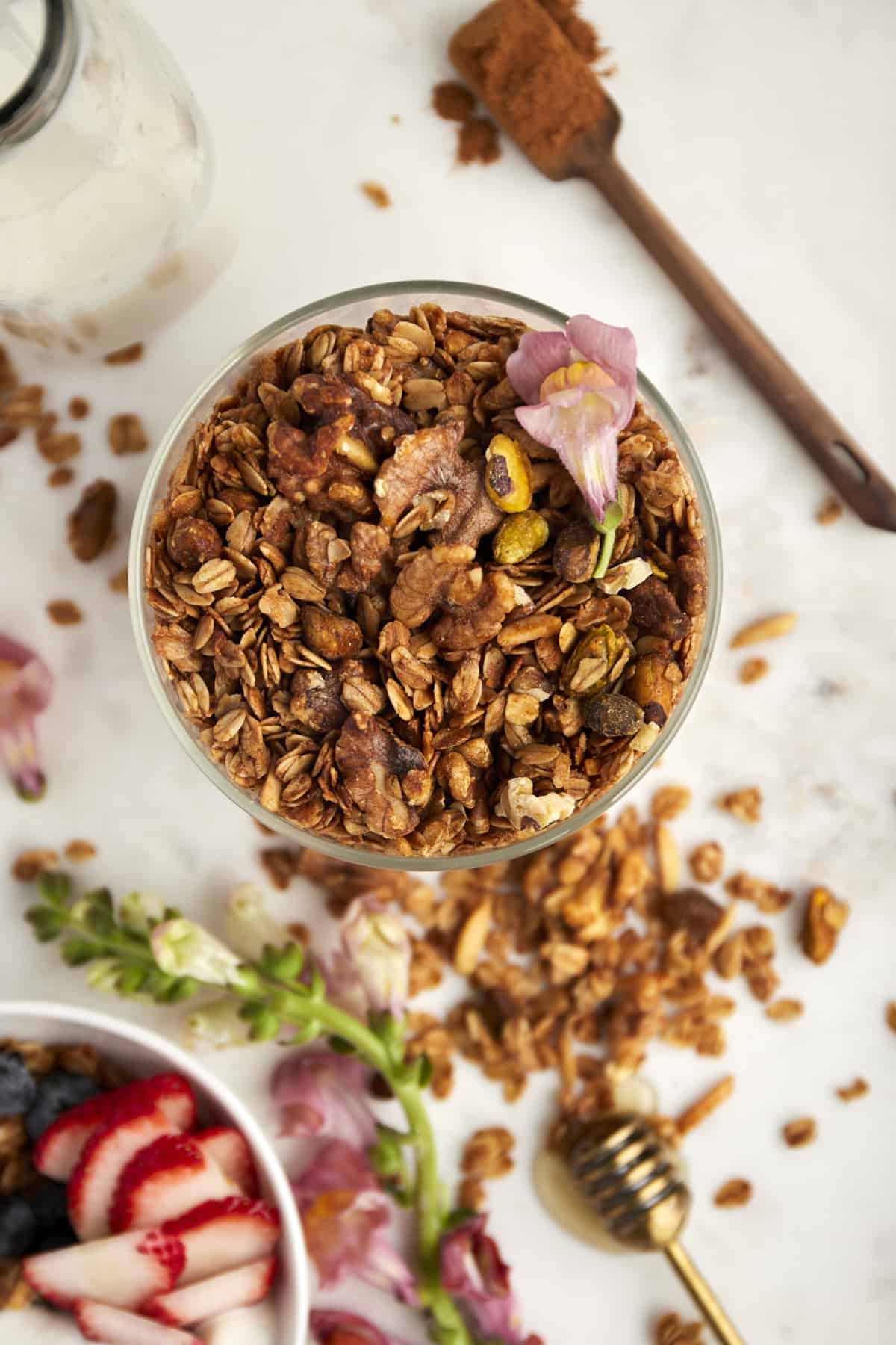 overhead image of a jar of baklava granola with berries and granola surrounding it