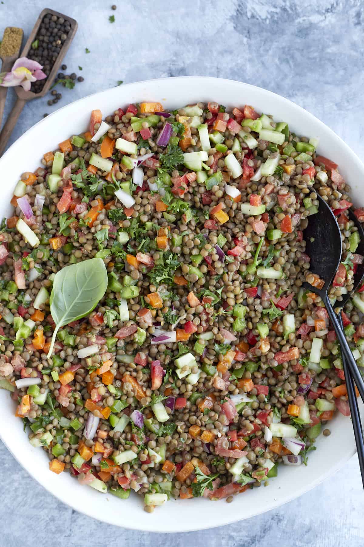 overhead image of a large white bowl full of lentil salad with veggies and a tahini dressing.