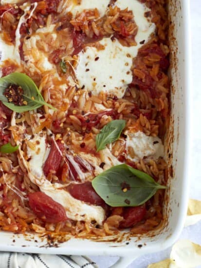 close up image of caprese baked orzo pasta with melted mozzarella on top