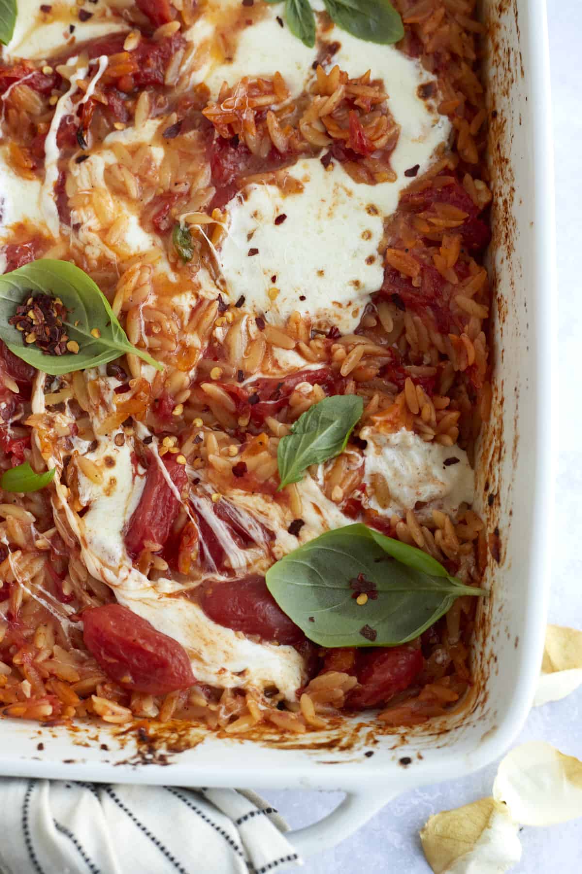 caprese baked orzo pasta in a casserole dish topped with fresh herbs