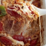 a serving of caprese baked orzo pasta being lifted out of a casserole dish