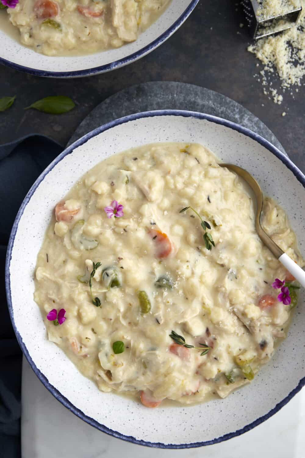 overhead image of a white bowl full of creamy chicken noodle soup.