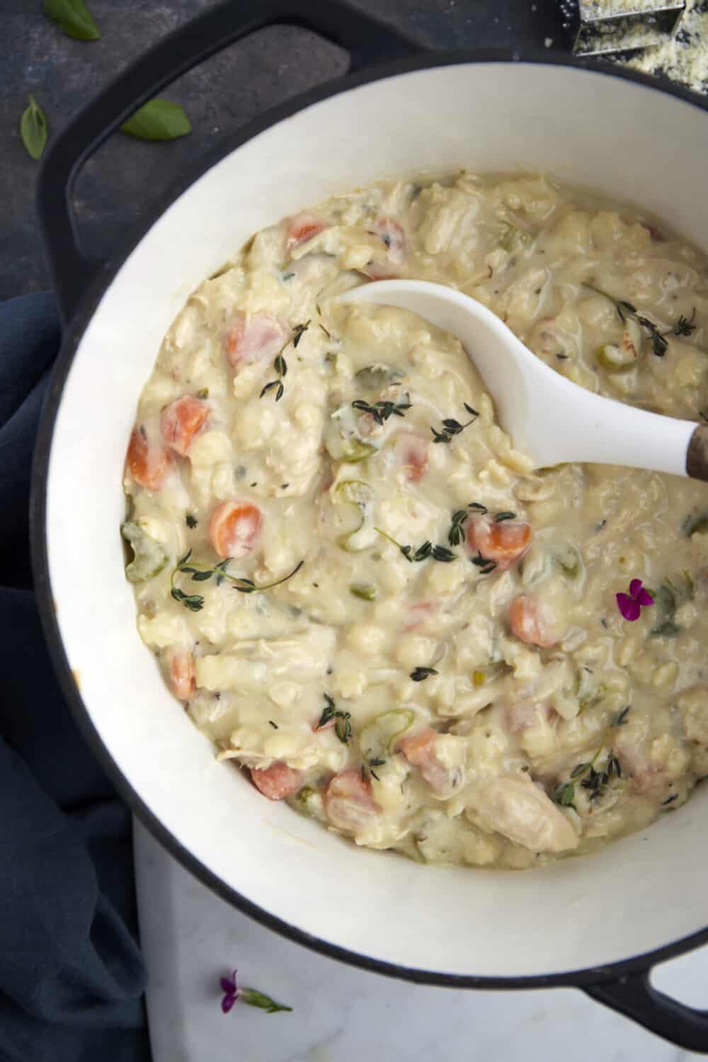 a bowl of creamy chicken noodle soup being scooped with a spoon.