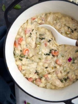a bowl of creamy chicken noodle soup being scooped up with a spoon.