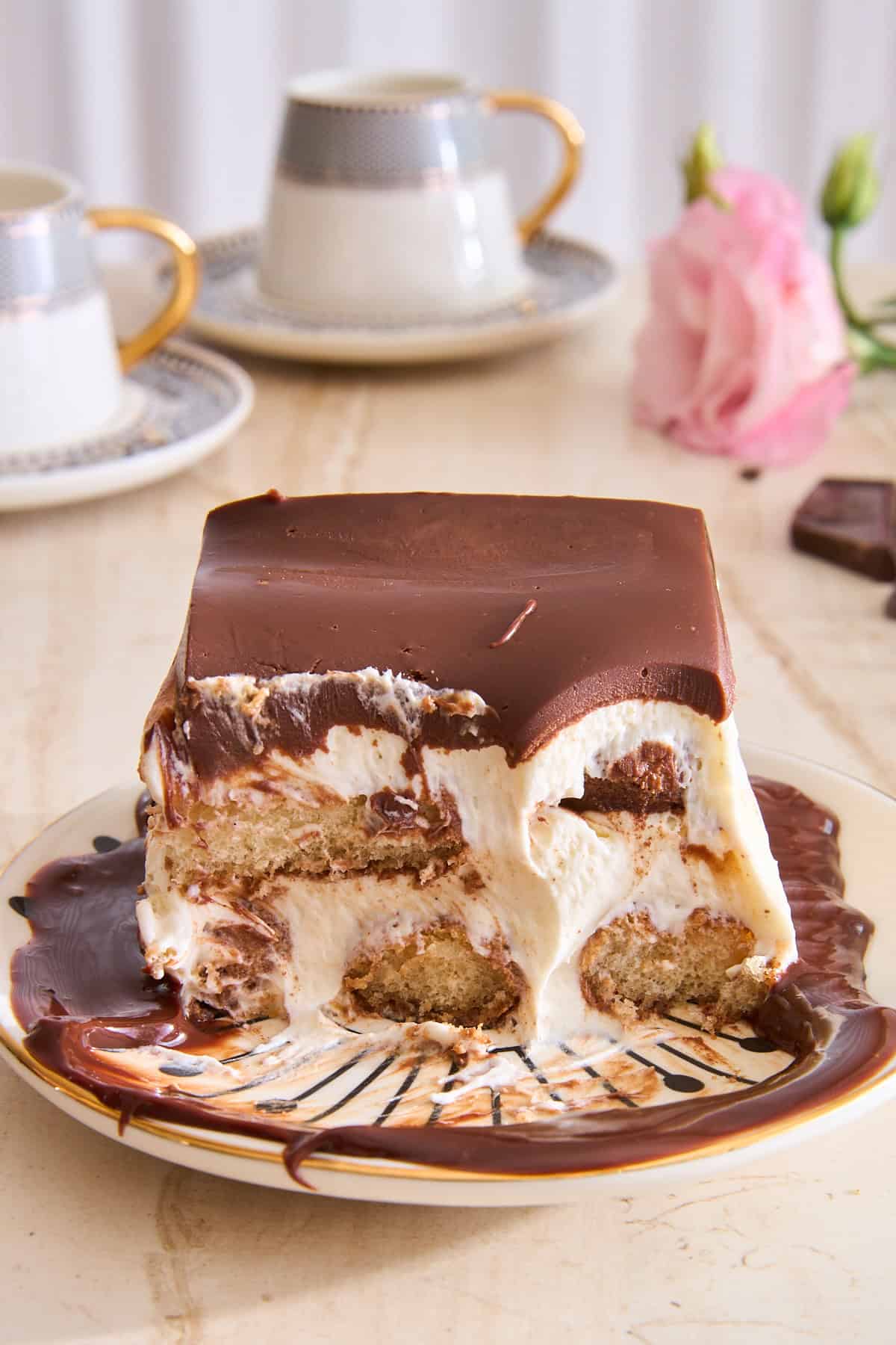 A slice of hot chocolate tiramisu on a plate with chocolate sauce