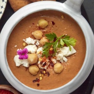 a bowl of Moroccan spicy tomato soup topped with feta, chickpeas, fresh parsley, and crushed red pepper flakes