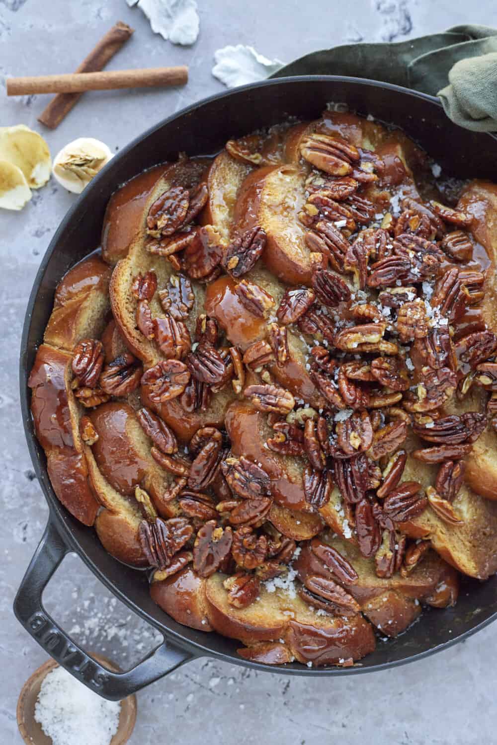 baked pecan pie french toast in a black skillet topped with pecans