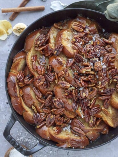 baked pecan pie french toast in a black skillet topped with pecans