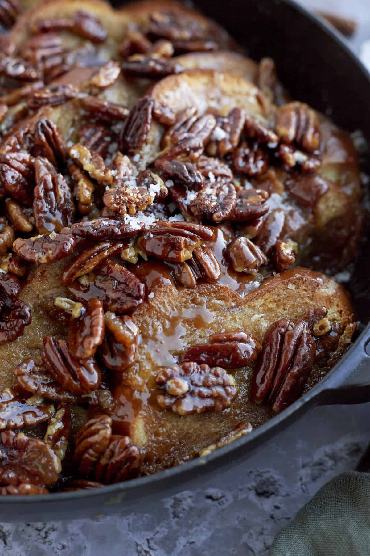 close up image of baked pecan pie french toast topped with sea salt flakes and pecans