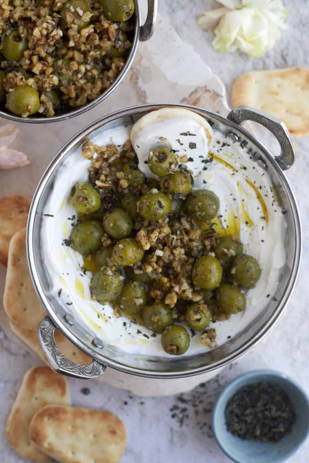overhead image of labne topped with marinated olives and pine nuts