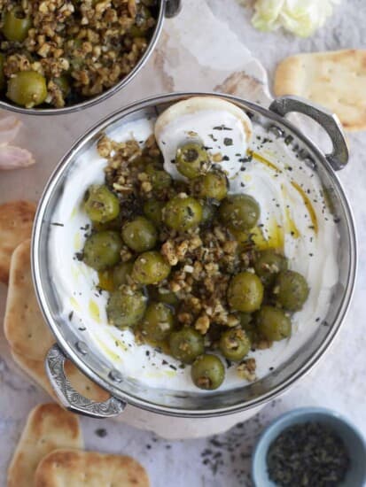 overhead image of labne topped with marinated olives and pine nuts