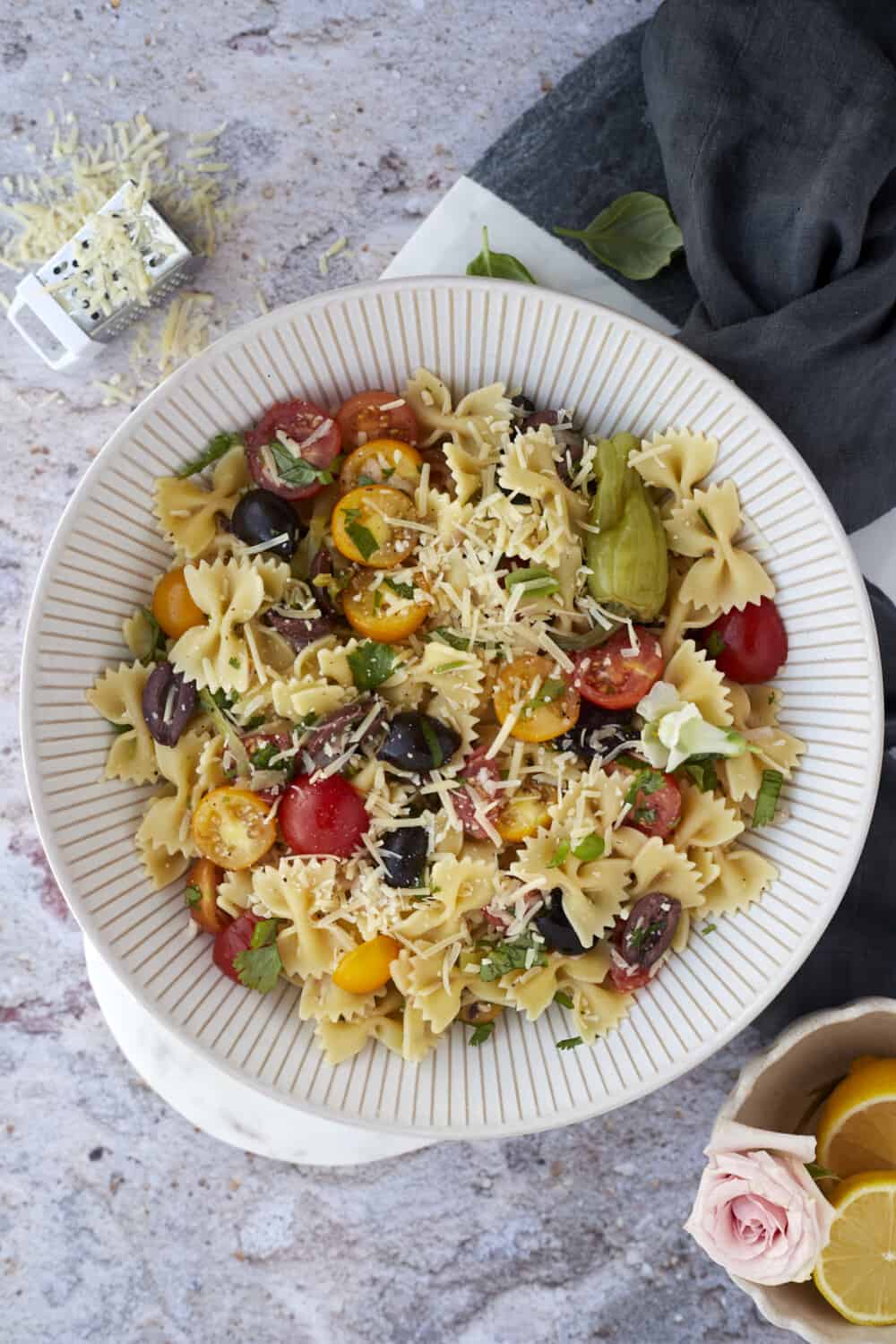 overhead image of warm Italian pasta salad in a bowl topped with shaved Parmesan cheese