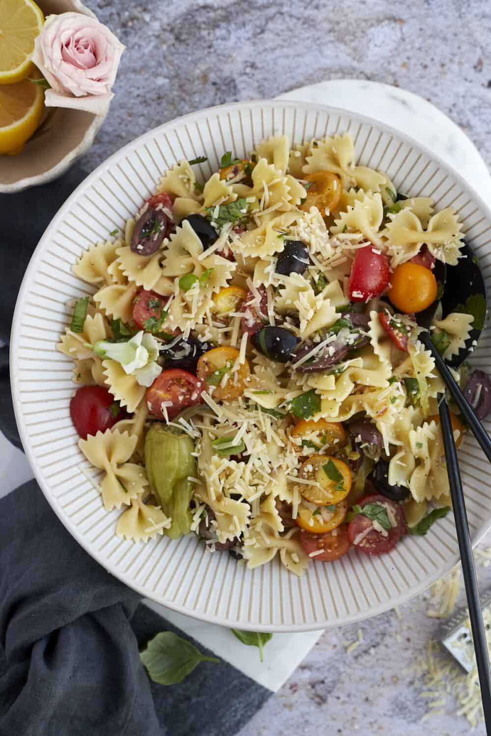 warm Italian pasta salad in a large bowl with serving tongs on the side