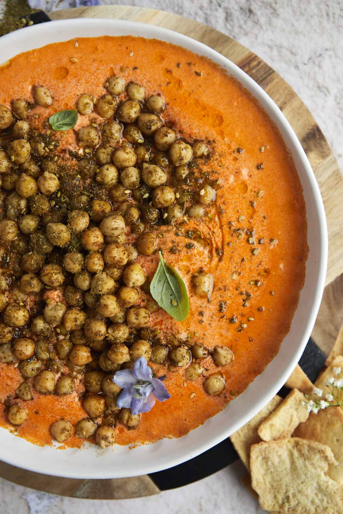 a white bowl of Roasted Red Pepper Feta Dip with Crispy Chickpeas on top 