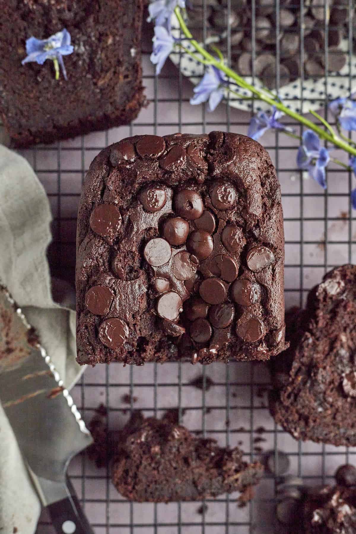 half a loaf of double chocolate banana bread on a wire rack with a knife in the bottom lefthand corner