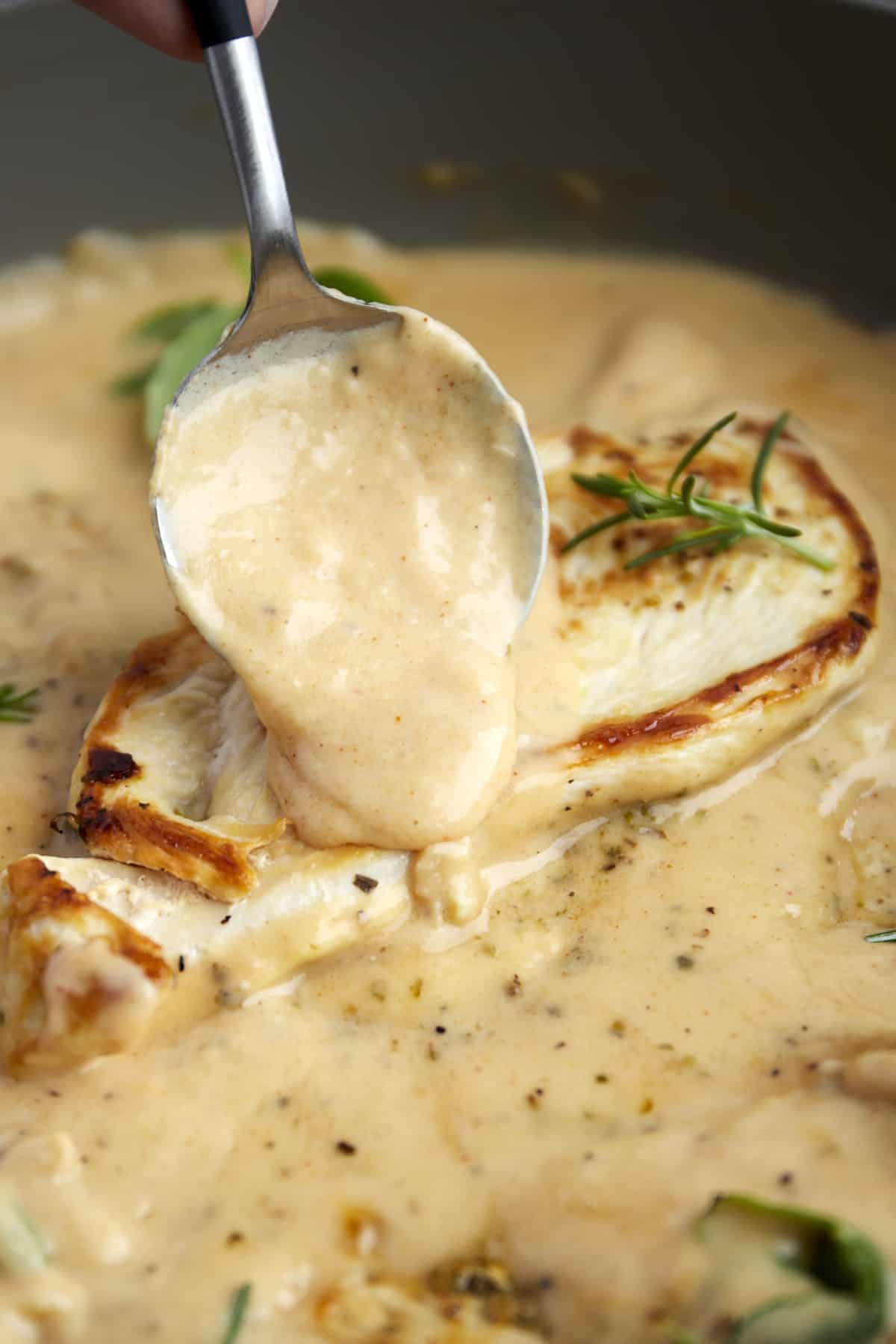 Cream sauce being spooned over chicken