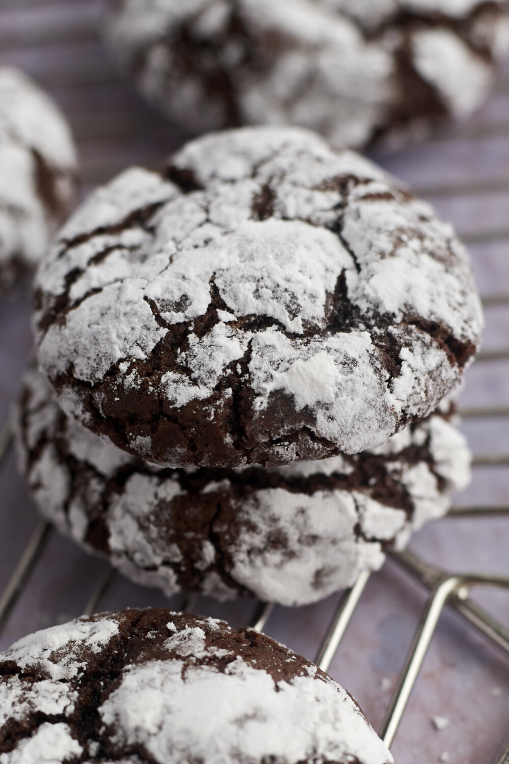 two chocolate crinkle cookies stacked on top of each other on a wire rack